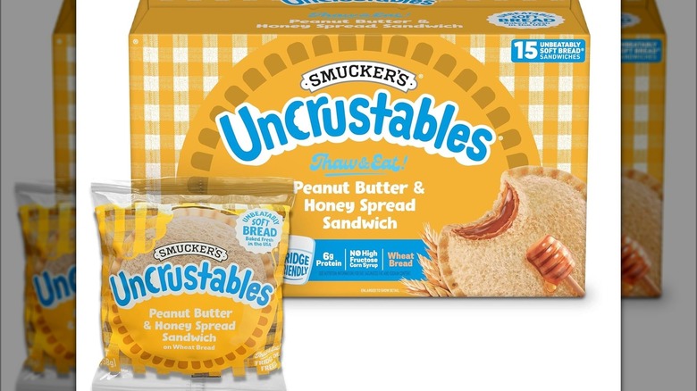 Box of Uncrustables sandwiches with an individually wrapped sandwich sitting in front of the box.