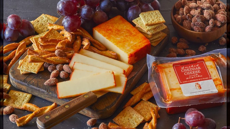 Cutting board with smoked cheddar cheese plus crackers, nuts, and other snacks.