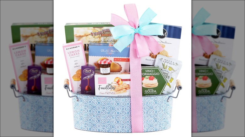 Decorative container with assorted snacks like cookies, chocolates, crackers, and cheese.