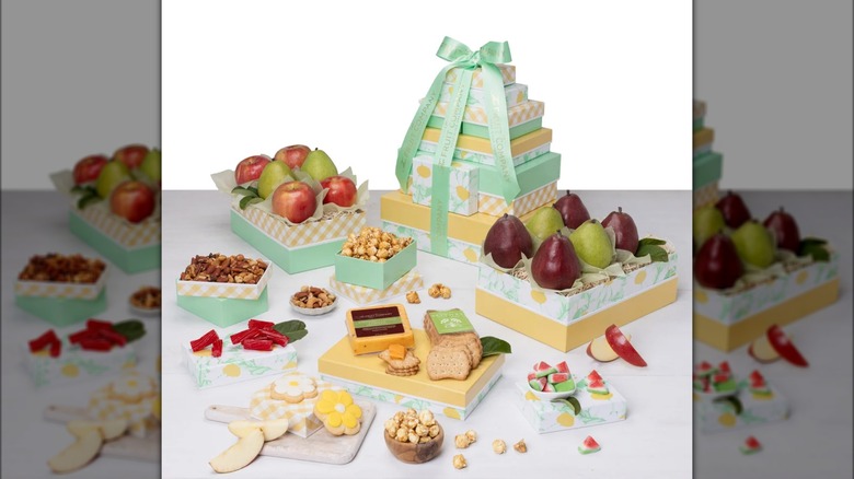 Multi-tiered gift set with assorted fruits, nuts, and other snacks.