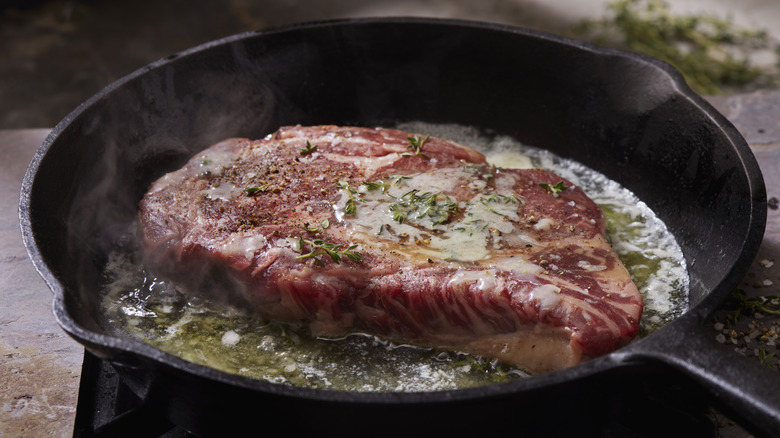 Searing a steak in a cast-iron pan.