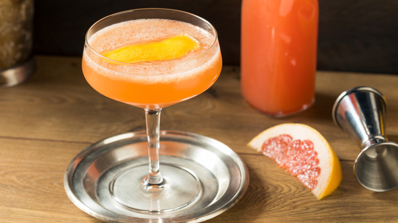 Brown Derby cocktail next to slice of grapefruit and jigger