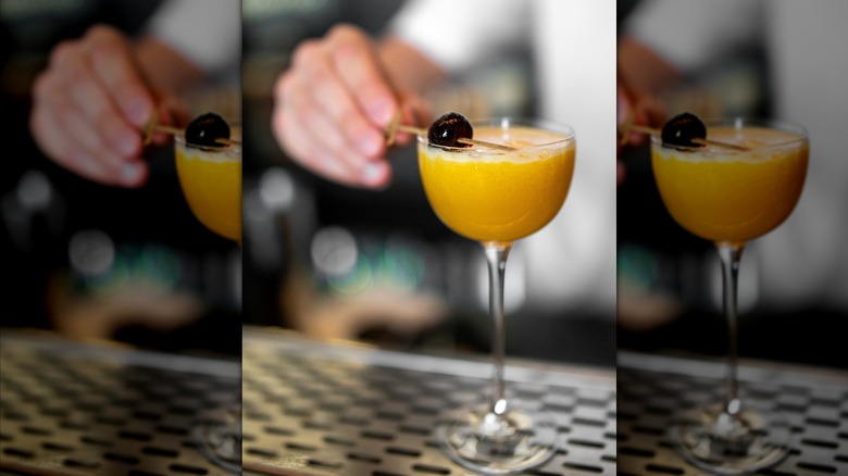 Bartender garnishing Man O' War cocktail with cherry