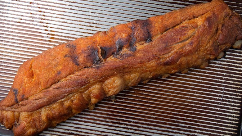 Freshly baked baby back ribs on an oven rack.