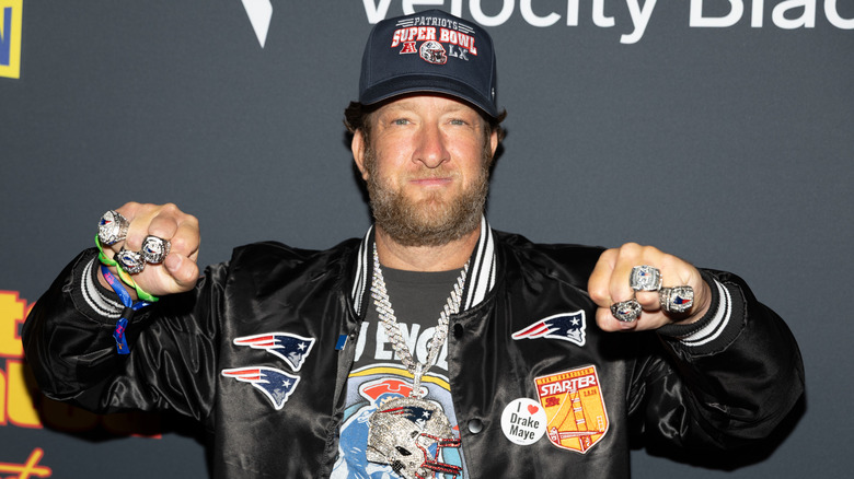Dave Portnoy onstage wearing a New England Patriots jacket and showing off his rings