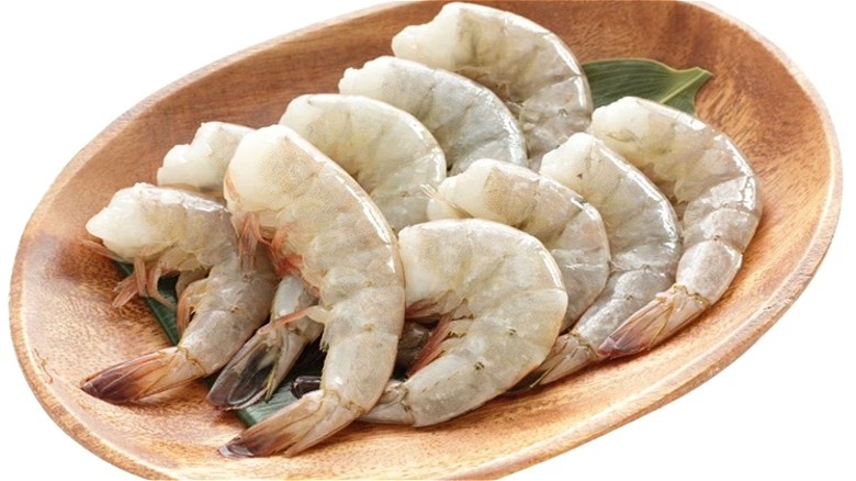Wooden bowl with several raw jumbo shrimp.