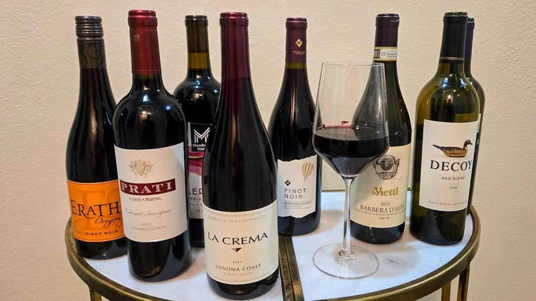 Red wine bottles that are available at Sam's Club with a glass of wine