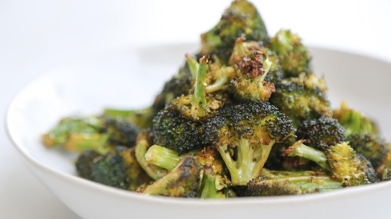 close up of roasted broccoli in a white bowl