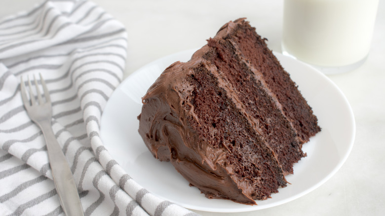 Slice of chocolate cake with chocolate icing on a white place