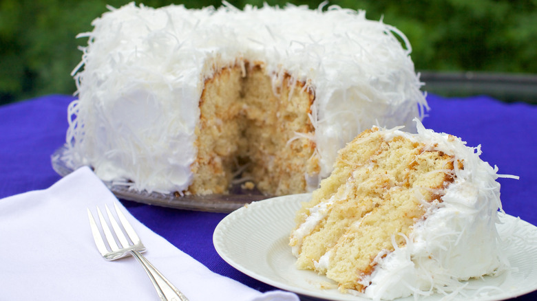 Coconut cake cut into with a slice on a white plate