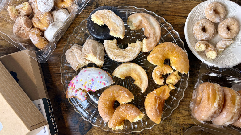 Several plates and boxes of donuts, filled with store-bought donuts for tasting