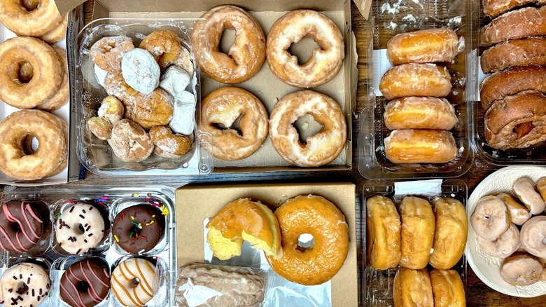 Assorted packages of glazed donuts on wooden table.