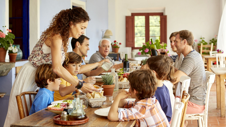 smiling mother serving food to large family