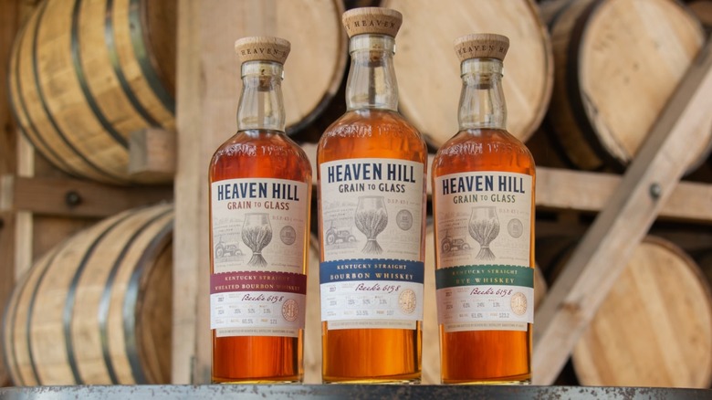 Three bottles of Heaven Hill Grain to Glass in front of whiskey barrels