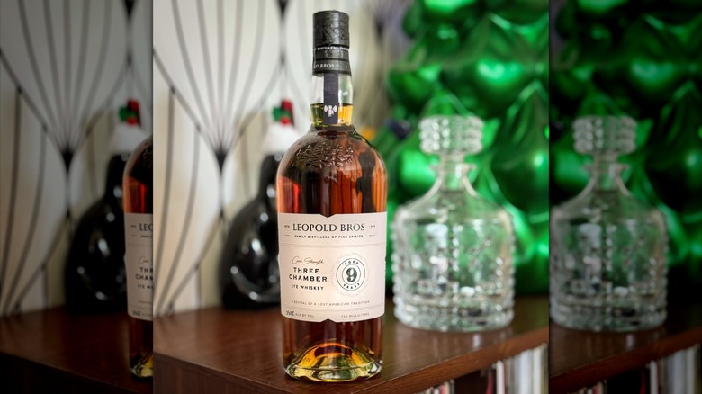 Bottle of Leopold Bros Three Chamber Rye on table with decanter blurred in background