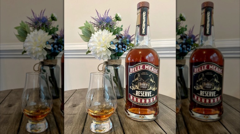 Bottle of Belle Meade Bourbon with glass on table with flowers