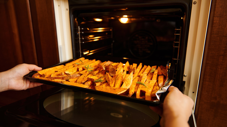 Person placing tray of fries in oven