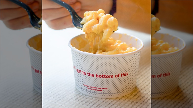 Person eating mac and cheese from a small cup at Chick-fil-A.