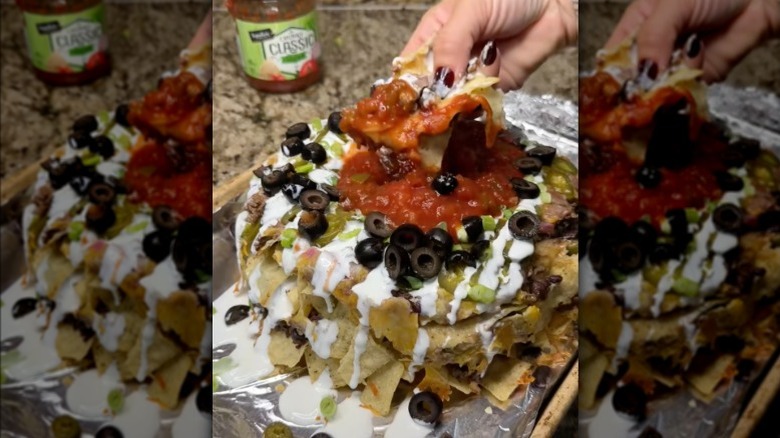 Hand scooping salsa with Bundt pan nachos.