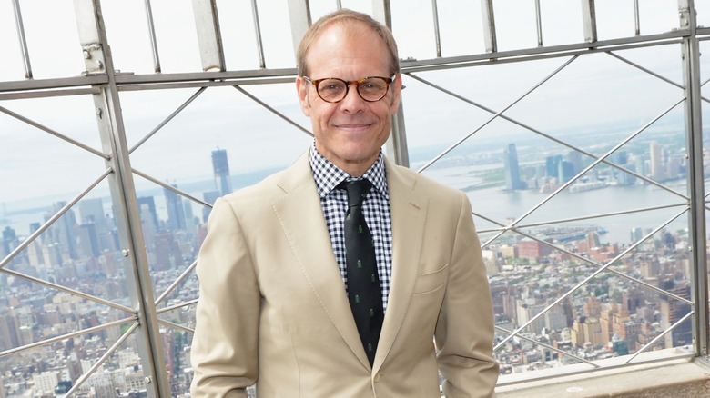 Alton Brown smiling on a skyscraper's viewing deck.