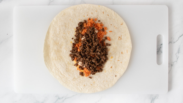 flour tortilla with cooked ground beef and orange-colored rice