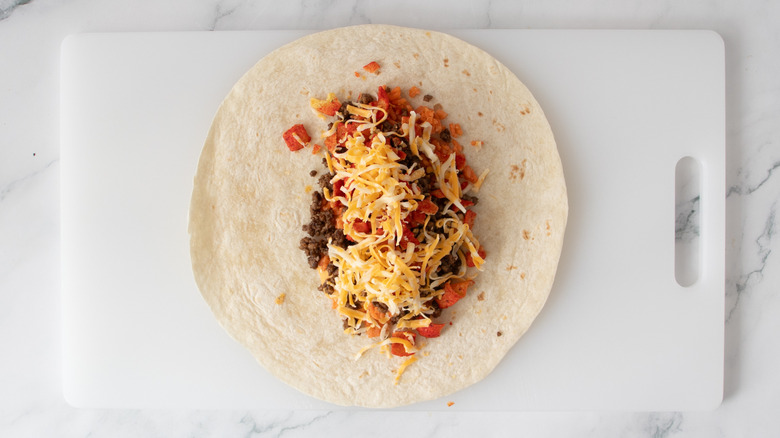 flour tortilla with cooked ground beef and shredded cheese