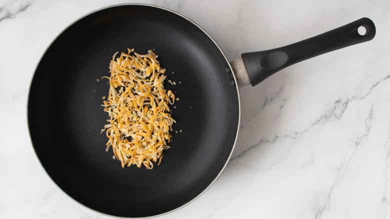 shredded cheese in a black frying pan
