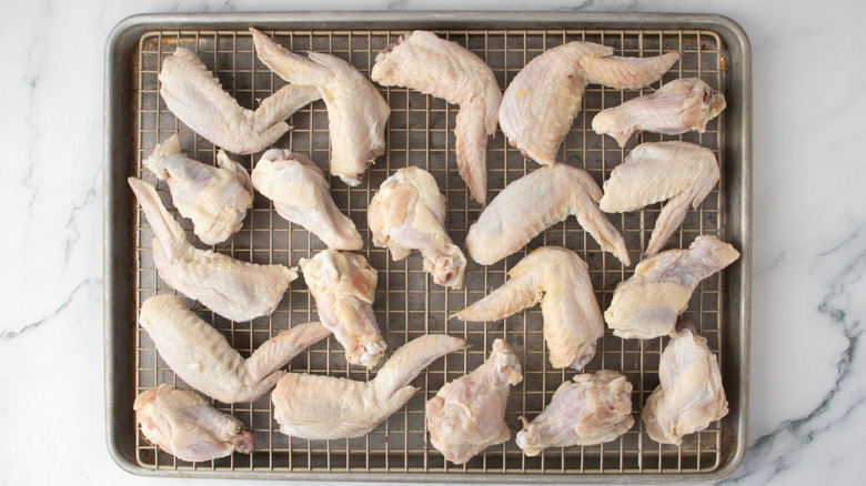Raw chicken wings on wire rack