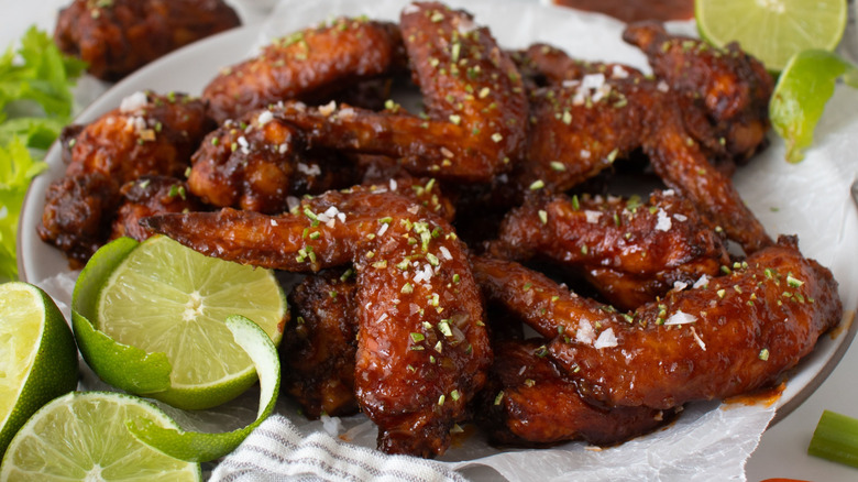 Platter of chicken wings surrounded by limes