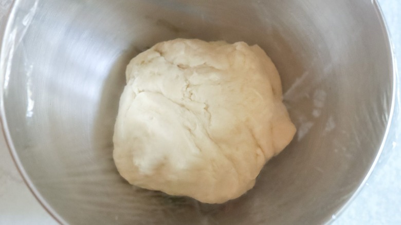 Dough ball in mixer bowl covered with plastic