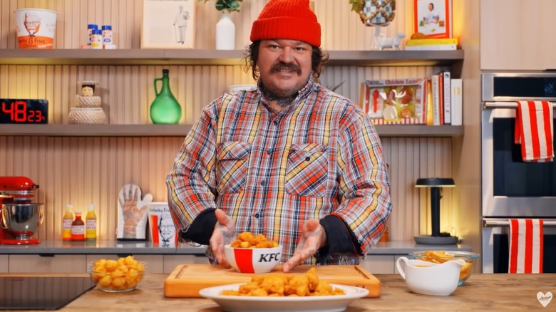 Matty Matheson shows Matty's KFC Cheesy Nuggy Gravy Bowl on his YouTube Channel kitchen, with platter of cheese curds and gravy boat on counter