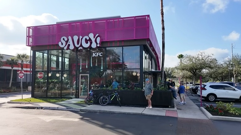 Storefront of Saucy! by KFC in Orlando, Florida by parking lot with cars, bicycles, and a few customers outside