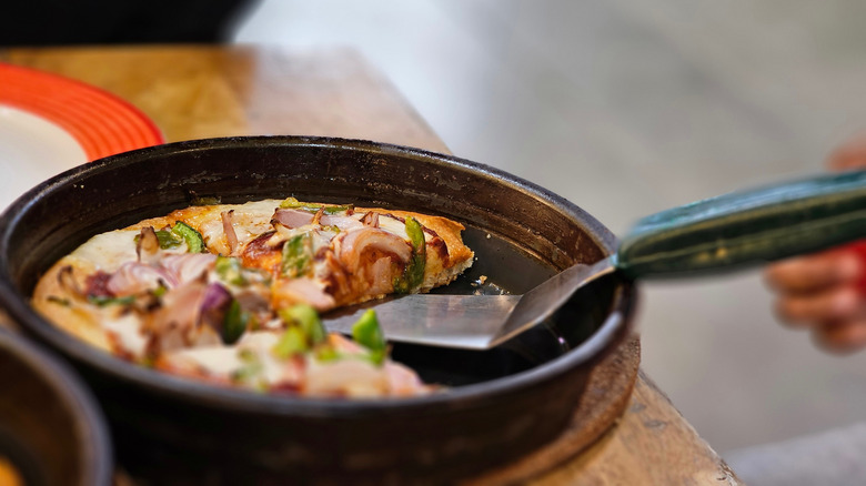 A Pizza Hut veggie pan pizza with a spatula removing a slice