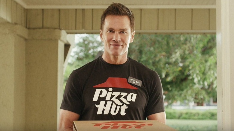 Tom Brady in a Pizza Hut uniform delivering a pizza