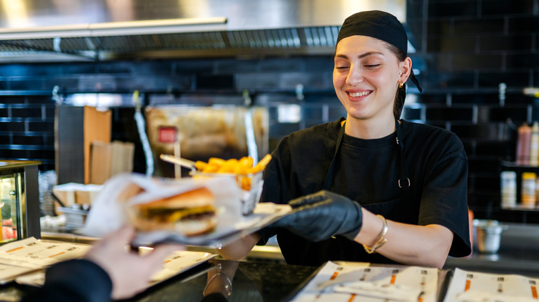 Cashier serving a generic fast food burger and fries