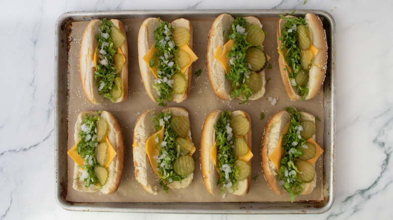 Hot dog buns filled with cheese, lettuce, onion, and pickles