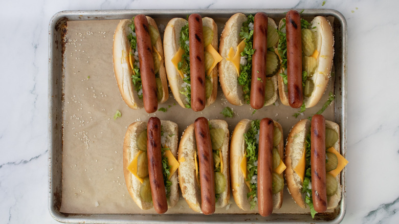 Big Mac hot dogs lined up on baking sheet