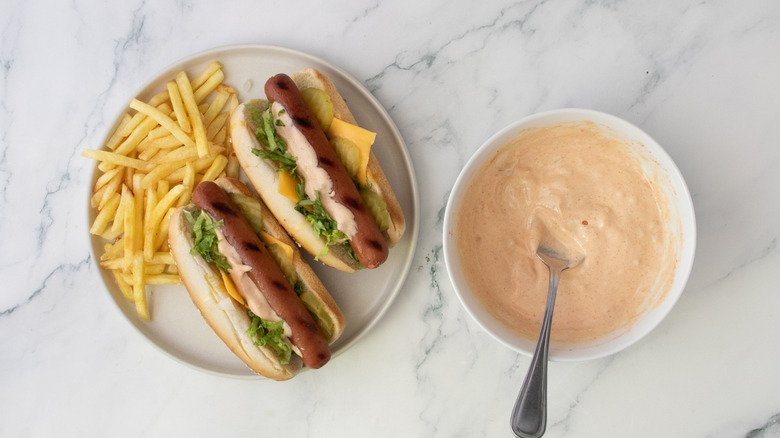 Big Mac hot dogs on plate with fries next to bowl of special sauce