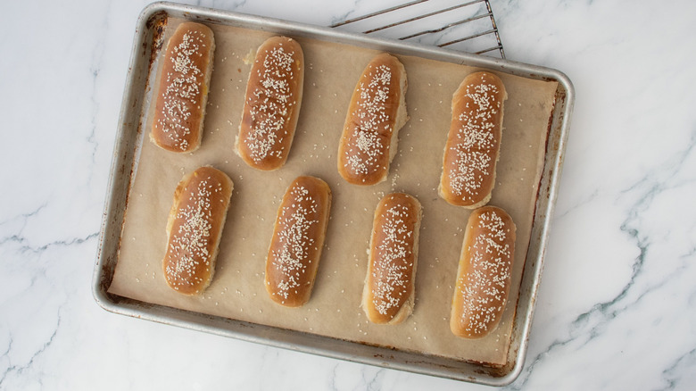 Sesame seed hot dog buns on baking sheet