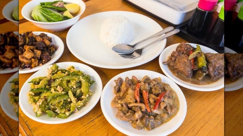 Assortment of Filipino dishes with plate of rice in the center