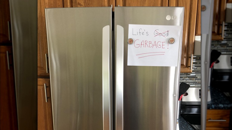 LG fridge with a sign that says "Life's Garbage" written on it.