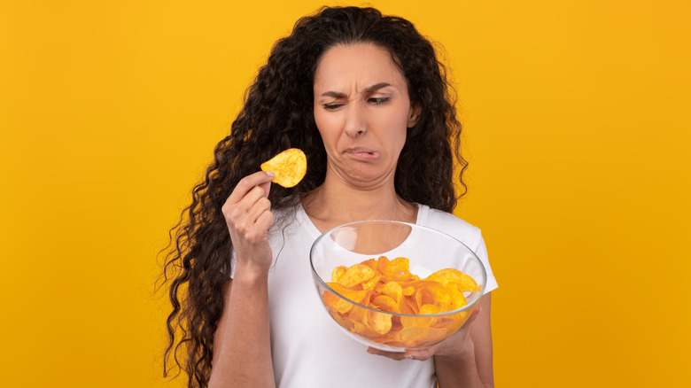 Person examining potato chip with disgust