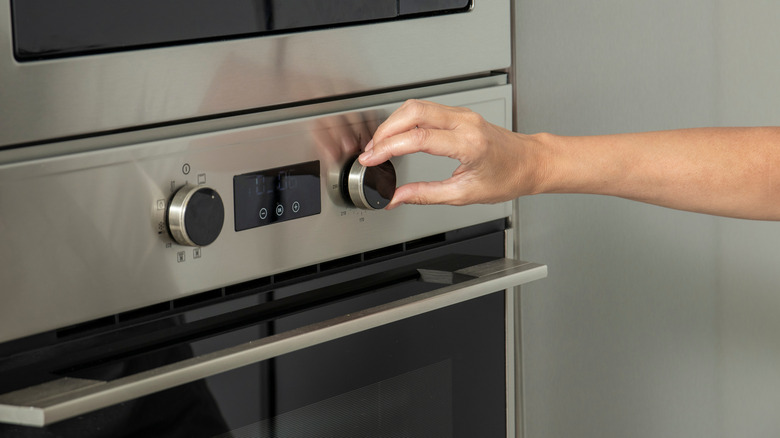 person's hand preheating oven