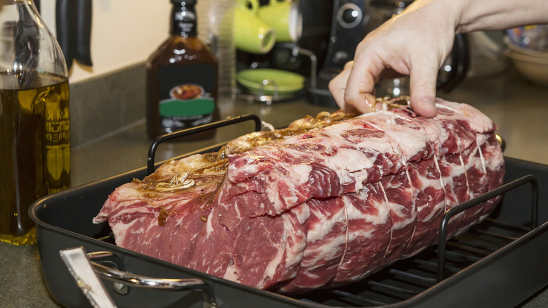 Male hand prepping prime rib tied in twine