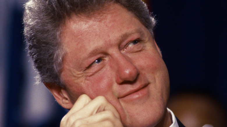 Bill Clinton smiling with his head in his hand.