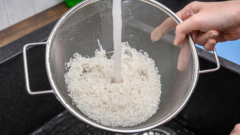 Washing rice in strainer under running water