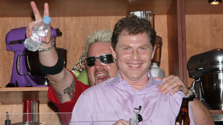 Bobby Flay and Guy Fieri sharing a funny moment on stage.