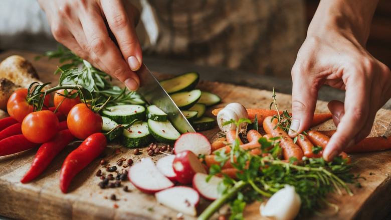 A chef chopping vegetables on a cutting board for a chopped salad.