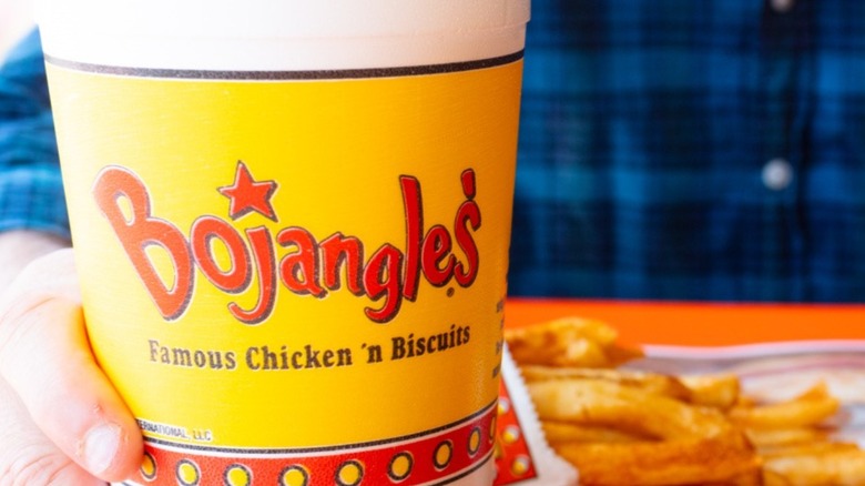 Hand holding a Bojangles cup with french fries