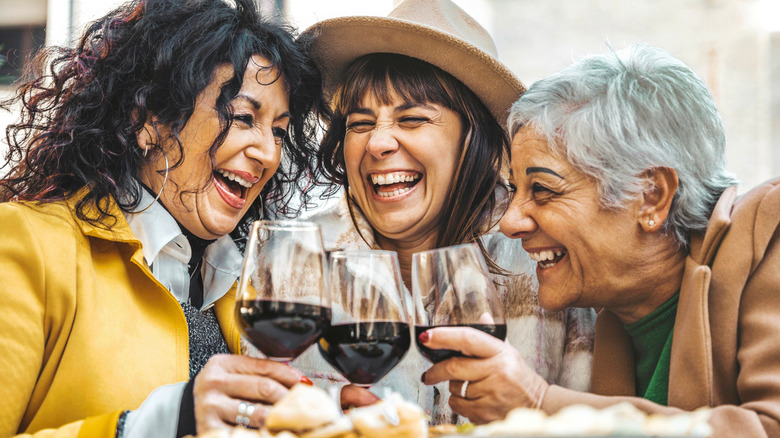 Three senior citizens enjoying wine with dinner at a restaurant.